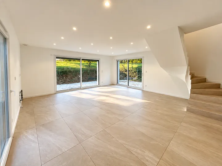 Séjour de la maison A avec baies vitrées et escalier