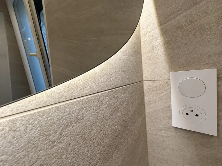 Miroir lumineux et prise murale sur carrelage