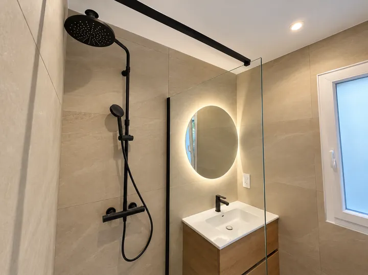Salle de bain avec douche noire et miroir lumineux
