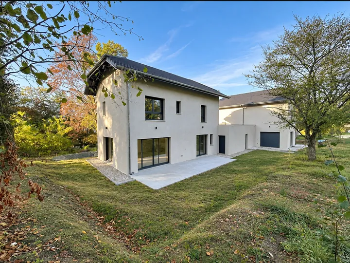 Maison côté jardin, baie vitrée et terrasse béton, arbres d’automne
